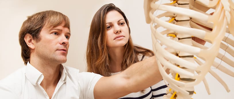 A teacher and student examining a model skeleton 